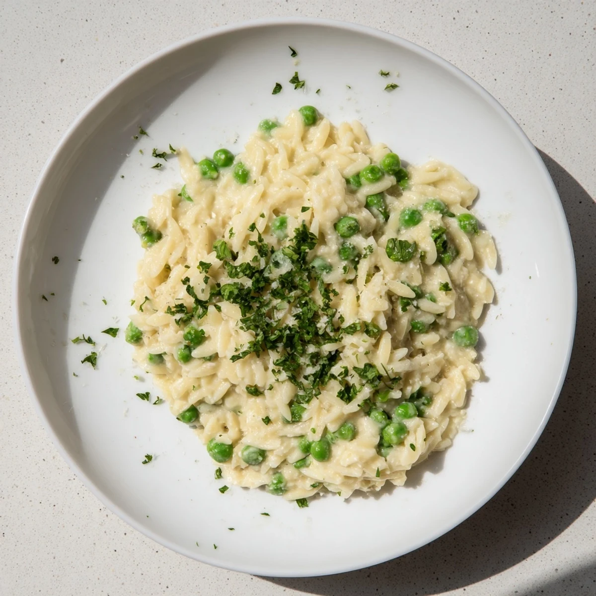 Creamy Parmesan Orzo's finished plate: a warm, inviting dish with green peas and a lovely cheese sauce.