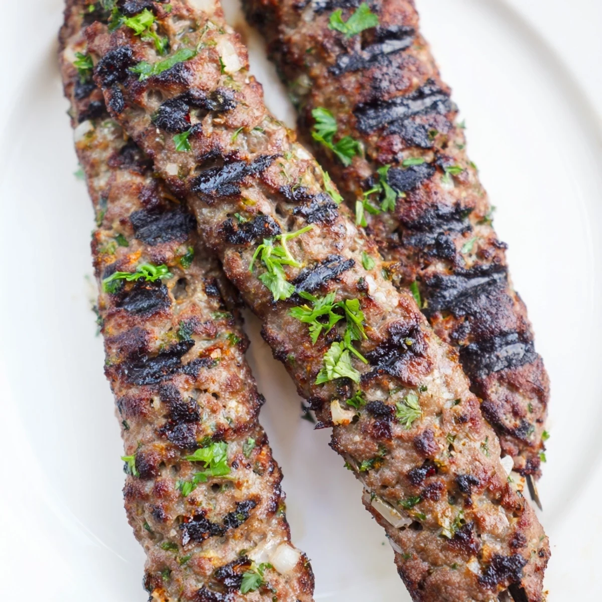 Tender Iraqi Kebab Tikka skewers, grilled to juicy perfection, are ready to serve with fresh herbs.