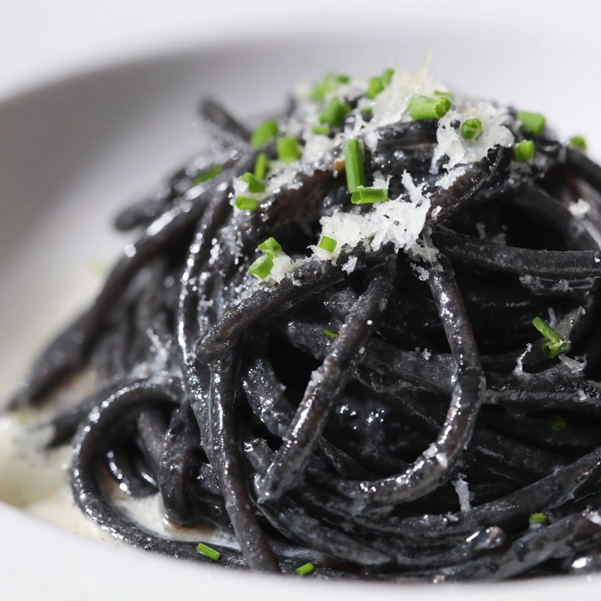Squid Ink Pasta in creamy sauce, topped with Parmigiano-Reggiano and fresh chives.