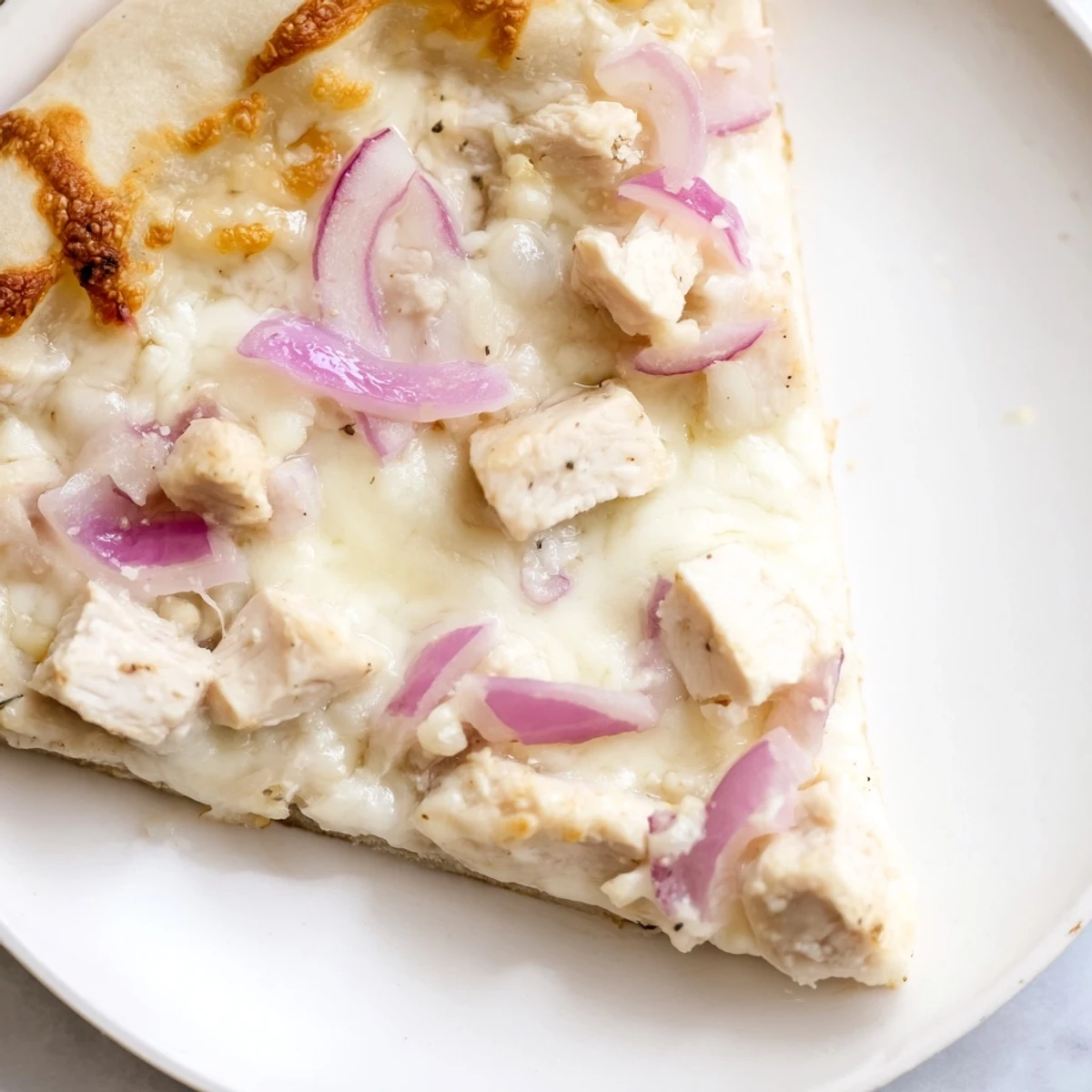 Golden crust topped with creamy Alfredo sauce, tender chicken, melted cheeses, and fresh parsley on a rustic cutting board.