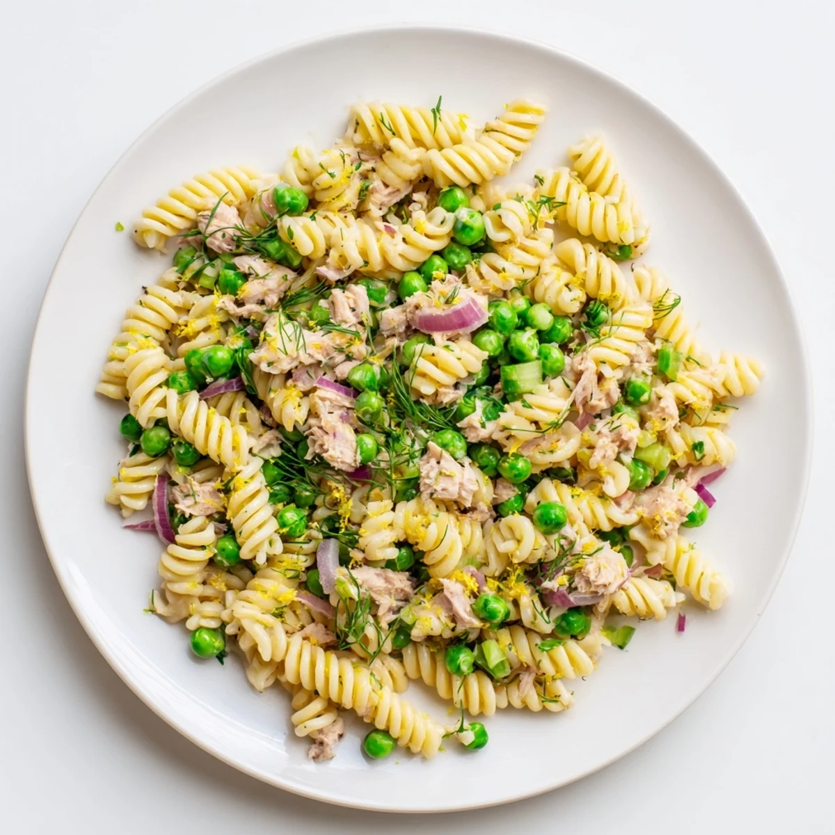 Fork holding a bite of Lemony Tuna Pasta Salad with lemon zest, tuna flakes, and fresh dill.