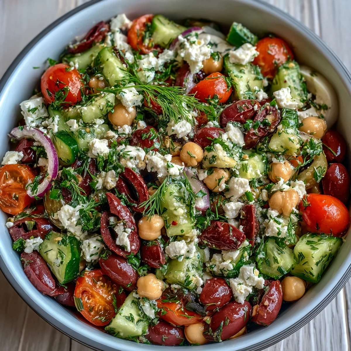 Vibrant Greek Bean Salad with lemon-marinated beans, crunchy cucumbers, sweet tomatoes, briny Kalamata olives, and creamy feta on a rustic platter.