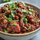 A close-up of Venison Keema Curry garnished with cilantro and served alongside fluffy basmati rice.  