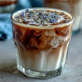 Two steaming mugs of lavender-infused oat milk latte, garnished with dried lavender buds for an elegant touch.