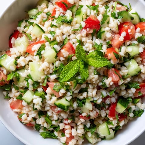 A close-up of homemade Bulgur Wheat Salad Tabbouleh featuring fresh parsley, diced tomatoes, and cucumber glistening with lemon dressing.