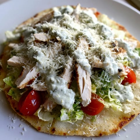 A close-up of Caesar Chicken Flatbread with grilled chicken, crisp romaine, and creamy dressing on golden crust.