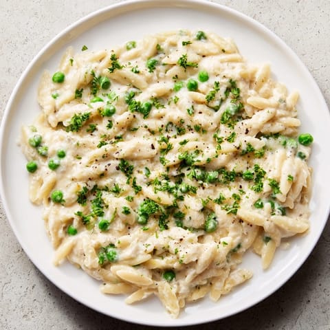 Freshly cooked Creamy Parmesan Orzo with bright green peas, ready to be garnished with parsley.