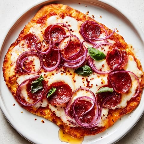 Golden, baked Hot Honey Pepperoni Flatbread topped with fresh basil, ready to be sliced and served.