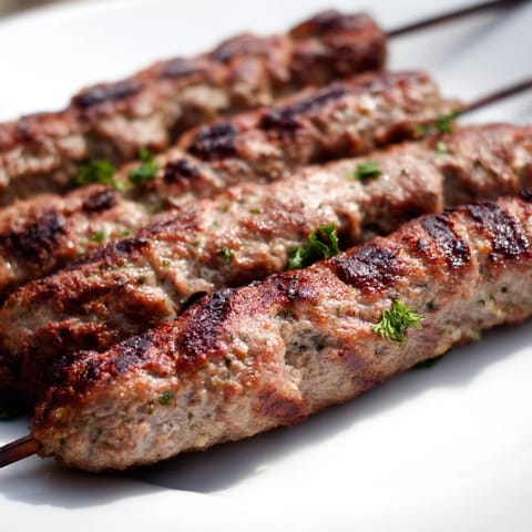 Smoky, savory Iraqi Kebab Tikka, glistening with spices, is surrounded by fresh tomatoes and onions.