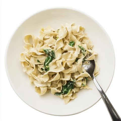 Wide egg noodles tossed in a rich cream sauce with garlic and Parmesan, ready to serve.