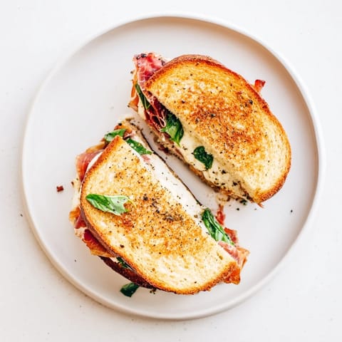 A close-up of the crispy prosciutto and burrata grilled cheese, showcasing the melted cheese and golden bread.