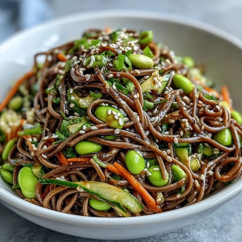 Hearty vegetarian Soba Noodle Bowl featuring chewy noodles, fresh vegetables, and a glistening sesame-soy sauce, ready to serve for lunch.