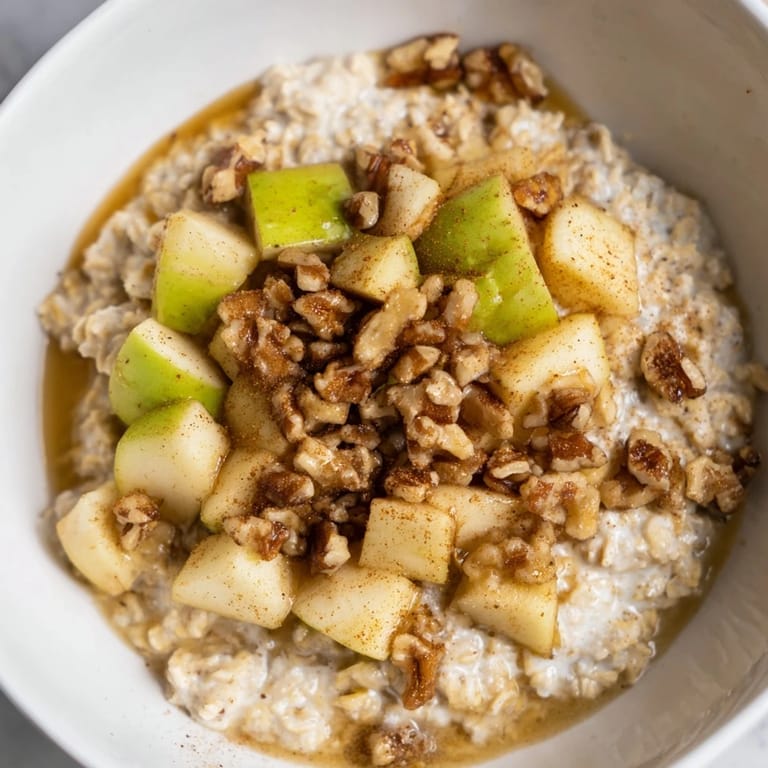 Creamy, cinnamon-infused apple pie oatmeal bowl with a golden apple topping, ready to be enjoyed.
