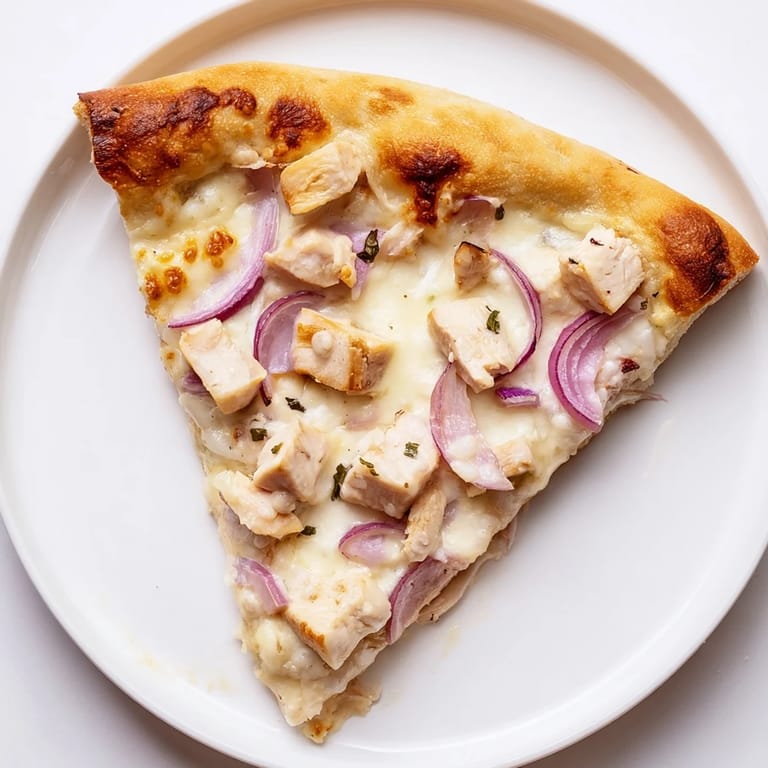 Sliced Chicken Alfredo Pizza reveals layers of savory chicken and gooey cheese, perfect for a weeknight Italian-American dinner.