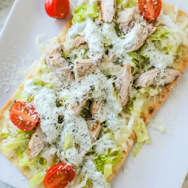 Golden Caesar Chicken Flatbread topped with fresh romaine, grated Parmesan, and juicy sliced chicken on a baking sheet.