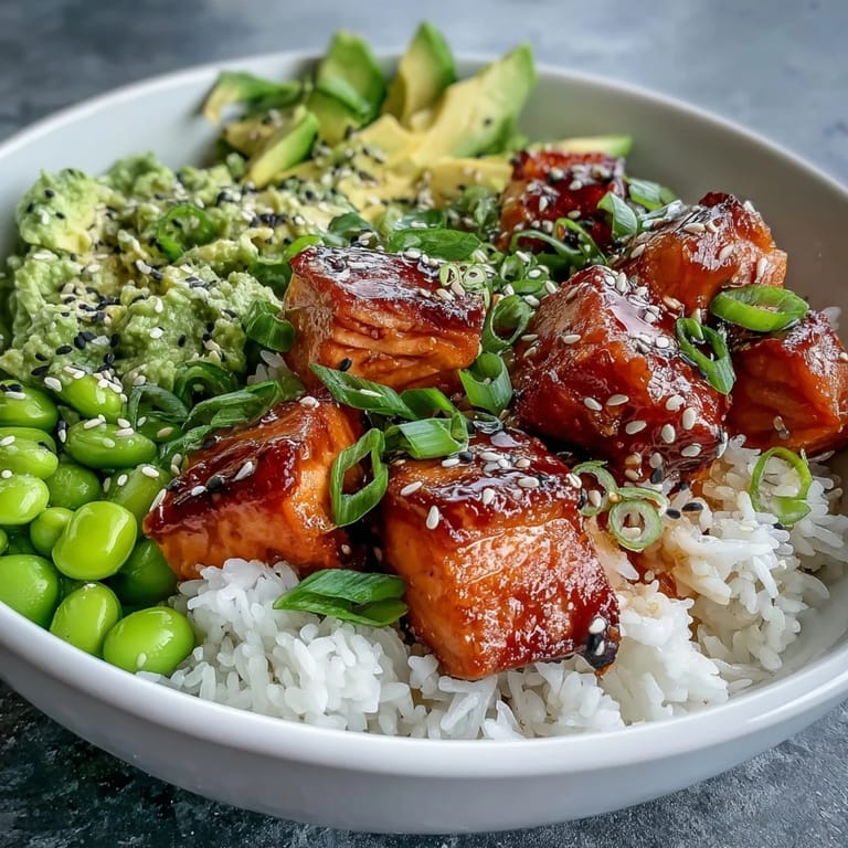 Perfectly baked salmon cubes top a nutritious Salmon Rice bowl with sesame seeds and sliced green onions.