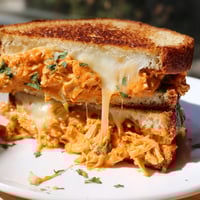 Golden, melted cheese oozing from a Savory Butter Chicken Grilled Cheese, a perfect comfort food creation.